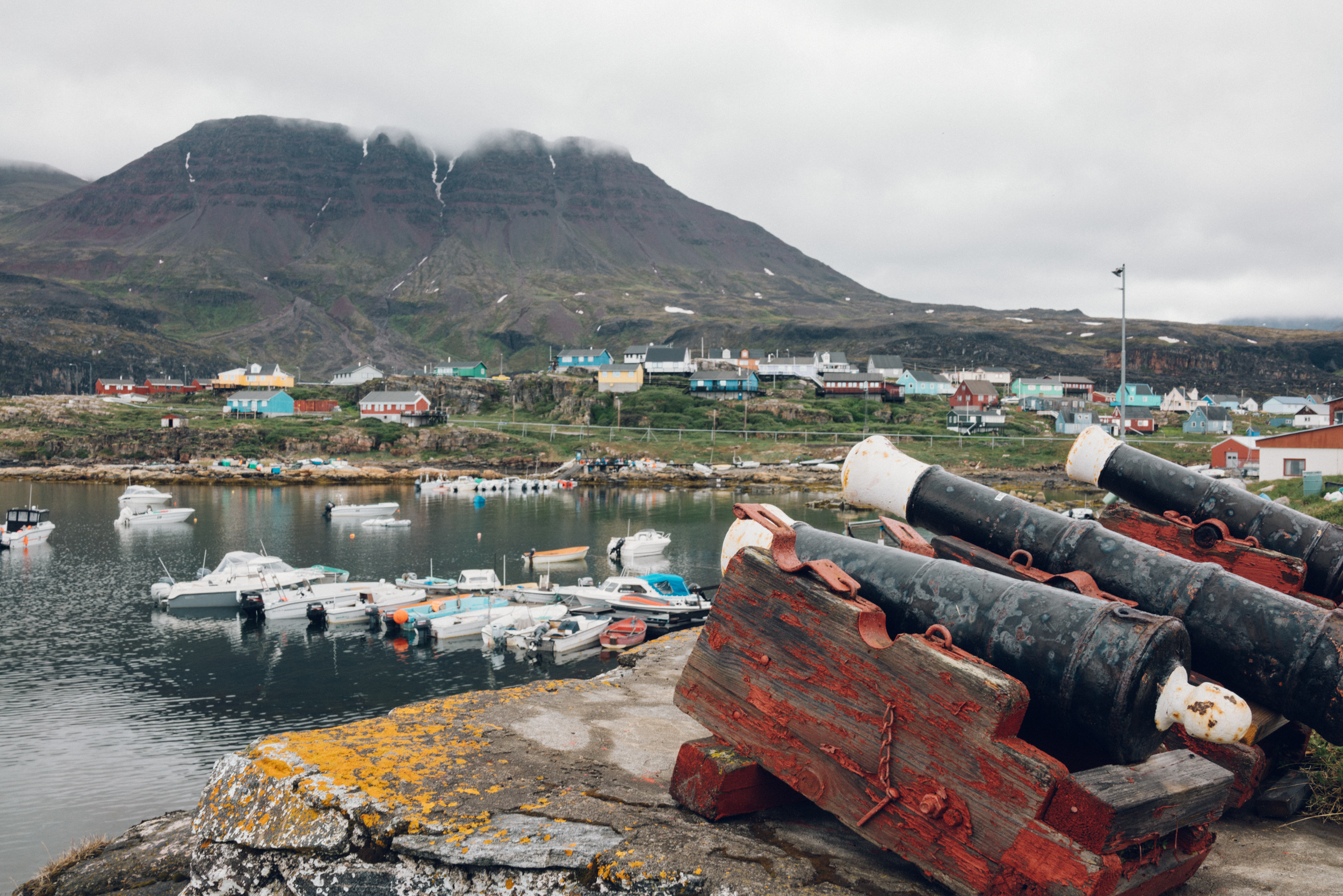 A hiker admiring the vast landscapes of Disko Island with glaciers in the background. 